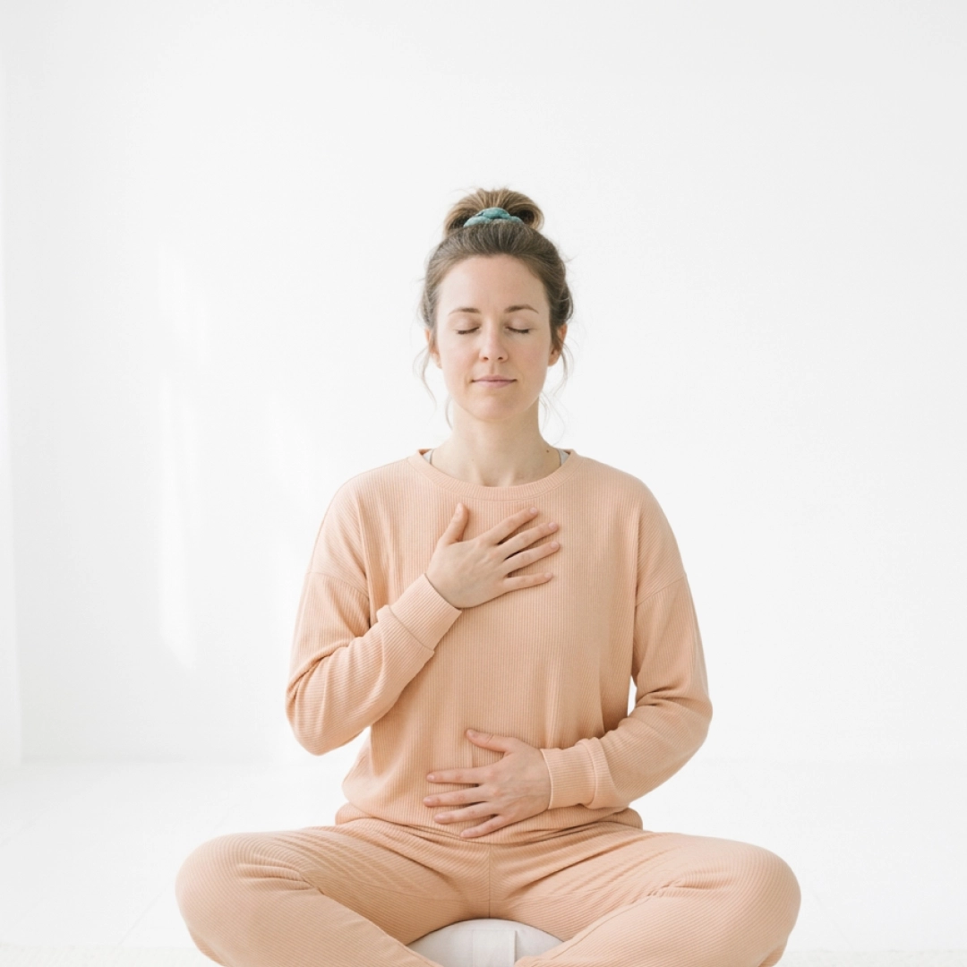 Woman practicing deep breathing with hands on chest and stomach in calm setting